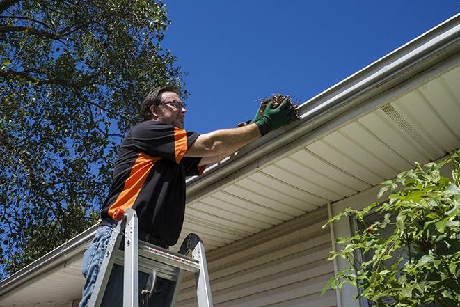 repairman sealing and reattaching a loose and sagging gutter in Adrian